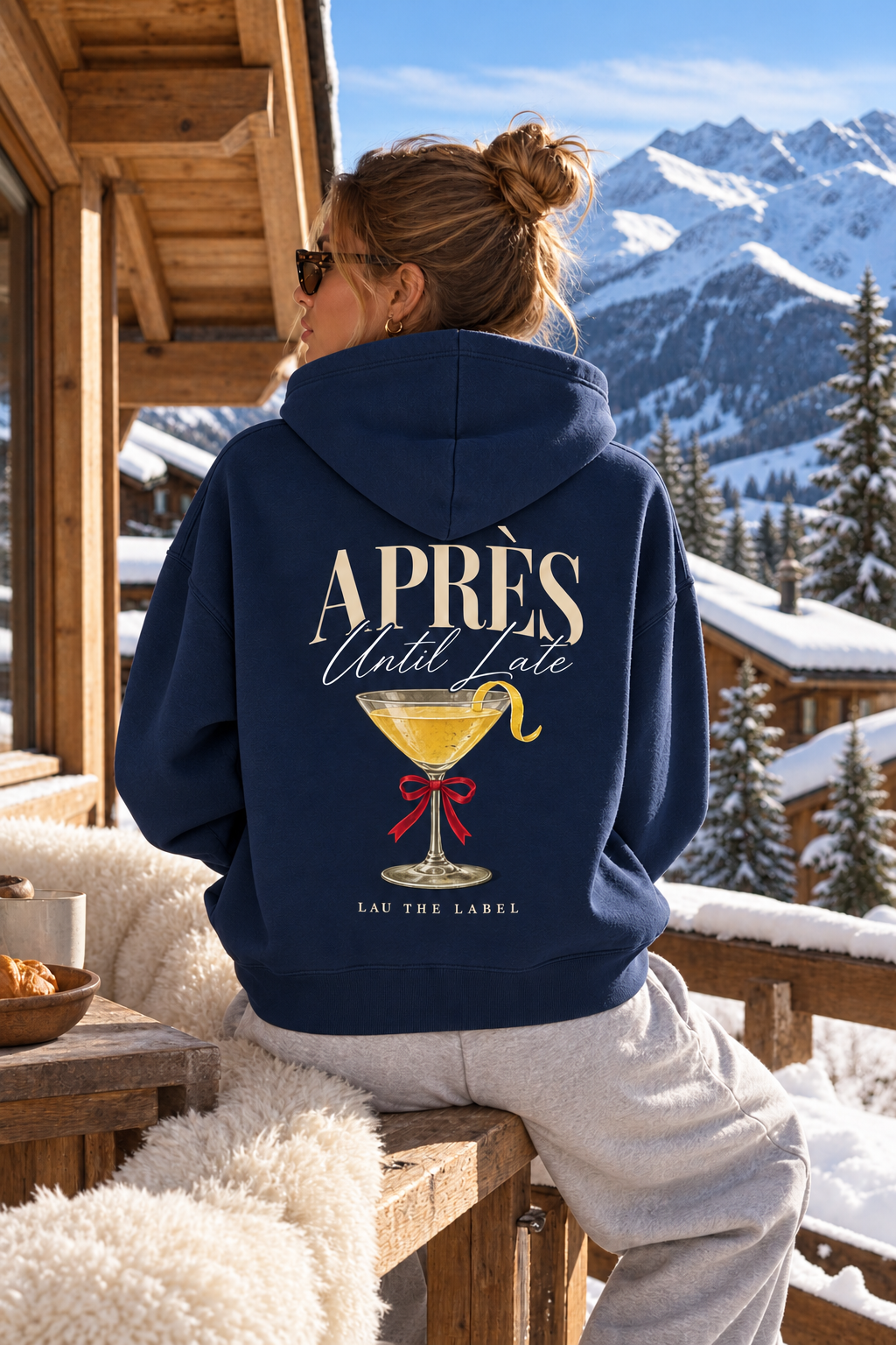 APRÈS UNTIL LATE HOODIE in French Navy, achterkant met cocktailprint, gedragen op een chaletterras